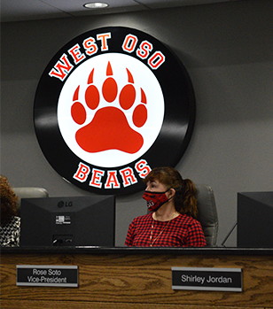 female-school-board-member-sitting-in-front-of-the-district-logo-during-a-meeting